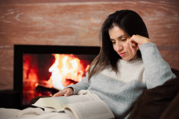 istock Woman enjoys reading a book from her sofa at home. 1944708405