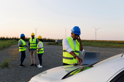 Engineers wearing uniform ,helmet hold document inspection work in wind turbine farms rotation to generate electricity energy