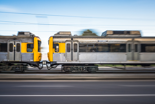Panning image as the carriages of a passenger train pass at high speed on a journey in Lisbon, Portugal..