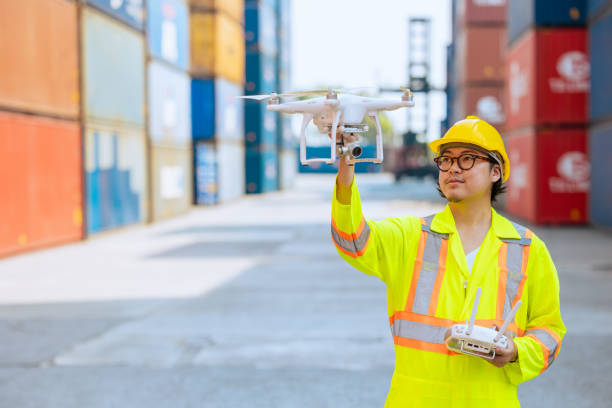Staff worker using Drone aerial imaging system in port container yard. UAV Patrol flying guard technology for survey and security safety area in logistics cargo.