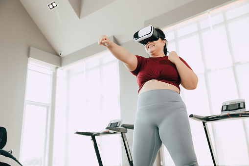 fat women with VR headset play visual reality sport game for exercise. people using modern technology for healtcare concept.