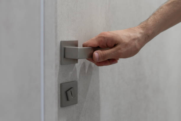 istock A persons hand is captured as it grasps a sleek, contemporary handle, preparing to open a light grey door. 1944756822