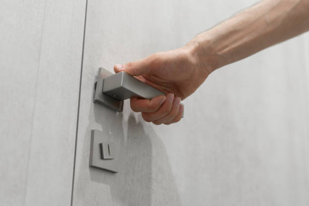 istock A persons hand is captured as it grasps a sleek, contemporary handle, preparing to open a light grey door. 1944756827