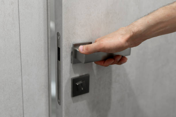 istock A persons hand is captured as it grasps a sleek, contemporary handle, preparing to open a light grey door. 1944757347