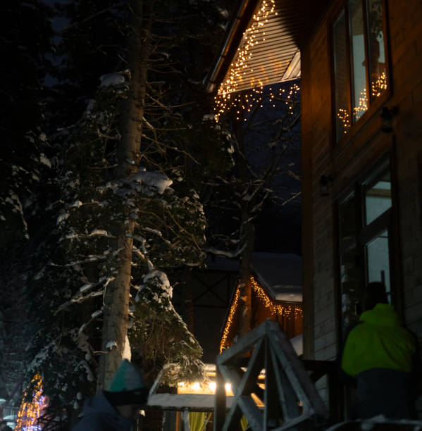 istock A charming A-frame cabin adorned with string lights stands out against the dark, snowy backdrop of a serene winter night. 1944765829