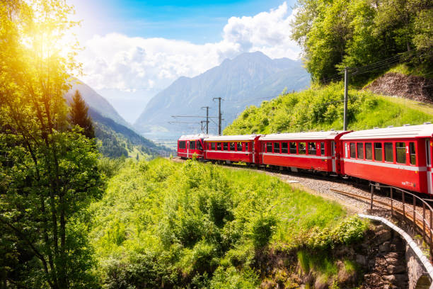 istock Red train moving in beautiful green summer forest in Switzerland 1944771471