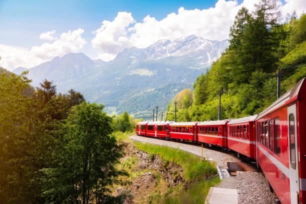 Red train moving in beautiful summer forest in Switzerland