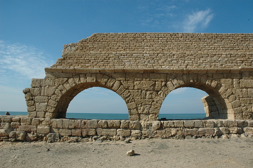 Stone arches and abutments of the Hadrianic aqueduct of Caesarea Maritima National Park along Israel's Mediterranean coast.
