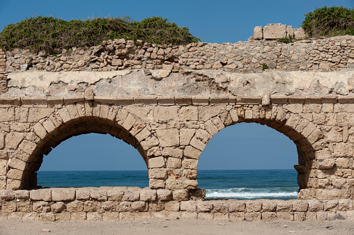Stone arches and abutments of the Hadrianic aqueduct of Caesarea Maritima National Park along Israel's Mediterranean coast.