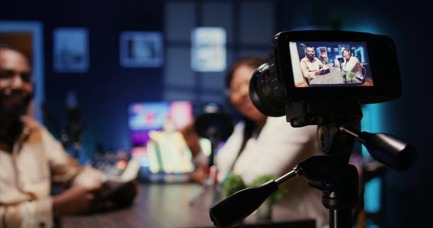 istock Focus on camera recording man on podcast in blurry background talking with guest 1944793663