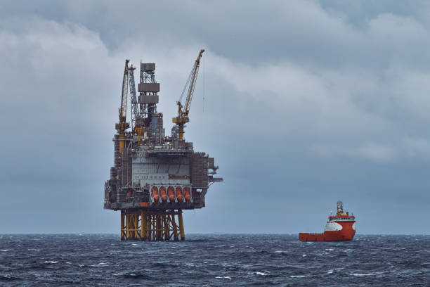 jack up drilling platform and supply vessel on the horizon in the sea. - oil rig storm jackup oil industry imagens e fotografias de stock