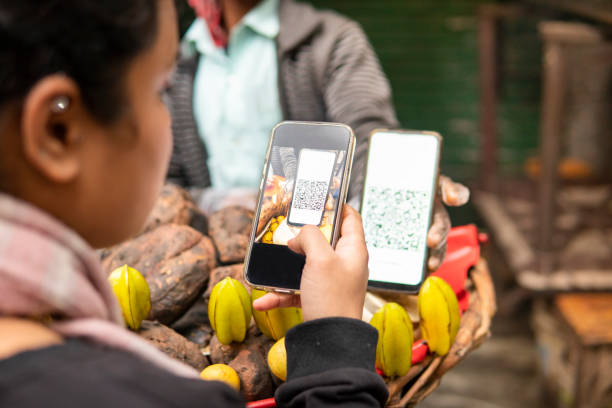 young woman scanning qr code with smartphone for digital payment at street shop. - red potato raw potato market red fotografías e imágenes de stock