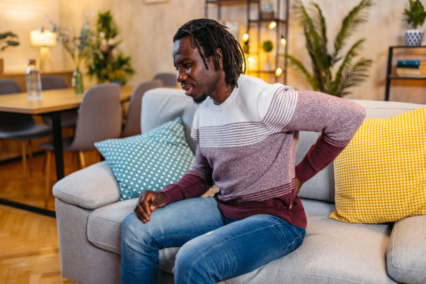 istock Young Man Having Back Pain While Sitting On The Sofa At Home At Night 1944803502