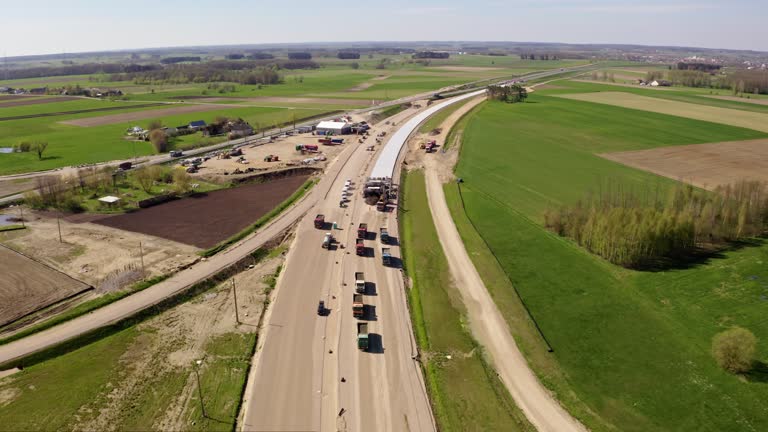 DJI drone flight view construction site of an asphalt highway. Trucks carrying construction materials