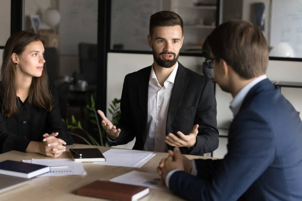 istock Serious young boss speaking to project managers at meeting table 1944813577