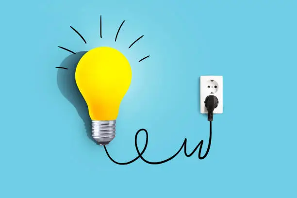 Creative idea, a yellow light bulb is plugged into a socket and glows on a blue background. Business and education. Brainstorm, concept. Think differently