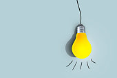 Creative yellow light bulb hangs and glows on a blue background. Think differently, concept. Successful project. Learning and Thoughts