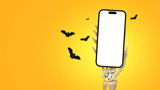 Skeleton holds a smartphone mockup in hand for design and copy space on an orange background with bats. Happy Halloween. creative idea. Application and game advertising