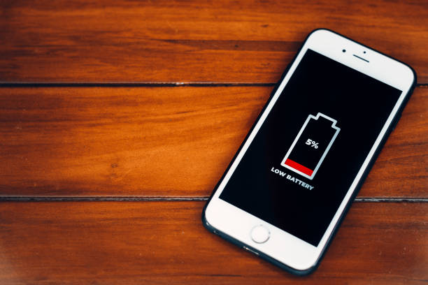 istock Cellular Problems and Energy Concepts. Smartphone with low battery icon on screen on wooden background. 1944834463