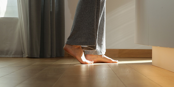 Barefoot woman on the wooden floor. Concept of the underfloor heating in the apartment.
