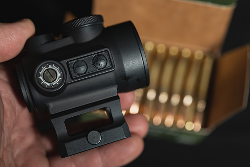 Red dot sight for a rifle in a man's hand, close-up photo. High quality photo