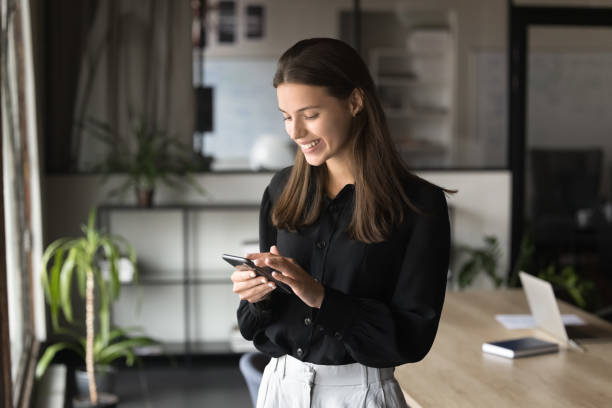 istock Cheerful beautiful businesswoman typing on smartphone, using professional service 1944869302