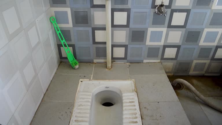 An Asian squat style toilet and bathroom in an unhygienic condition. India