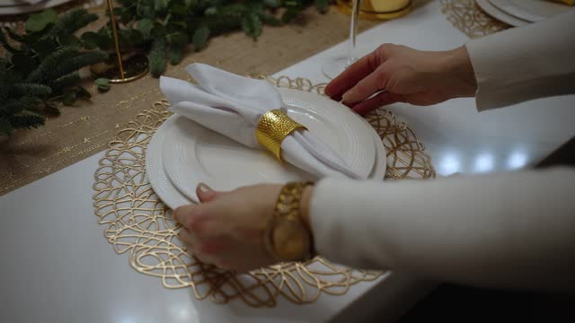 Table setting with cutlery. A woman puts plates on the dining table with her hands