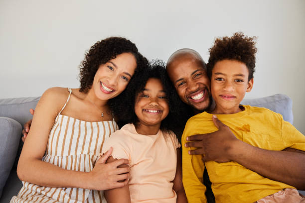 istock Smiling parents sitting with their cute little children on a sofa 1944896162