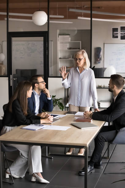 istock Serious senior boss woman talking to group of workers 1944901916