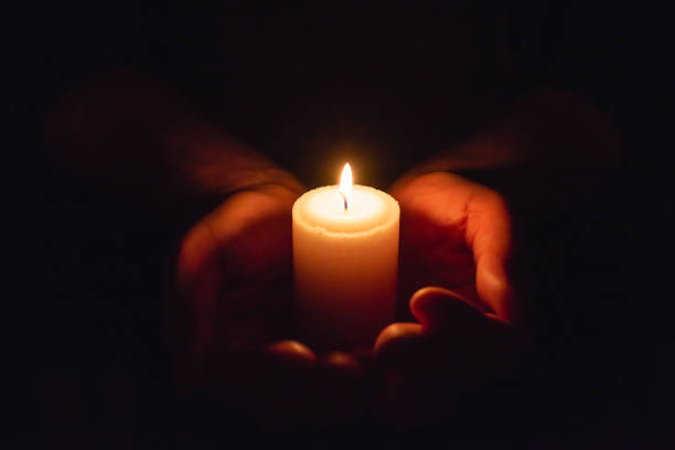 istock Hands holding burning candle in dark like a heart.Selective focus,black background. 1944969881