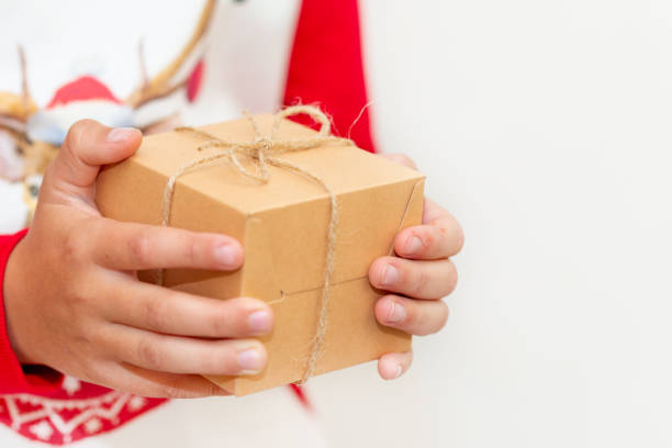 istock Young boy hands in pullover holding Christmas gift box on gray background.Christmas and New Year banner.Copy space. 1944972019