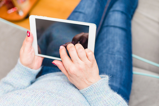 Woman using tablet and sitting on sofa,or couch.Woman using tablet at home in living room. Mockup for your text.Selective focus.