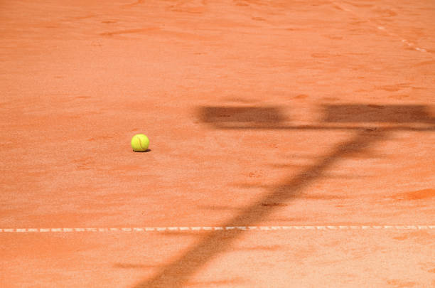 Abandoned tennis balls on the court at noon