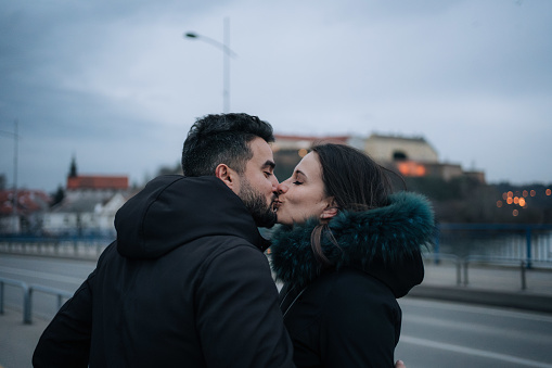 Moment of kissing happy couple while they walking to the brige