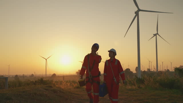 team of maintenance engineers walking on a wind turbine field, electrician or technician for wind turbine inspection and maintenance. Environmental and environmentally friendly