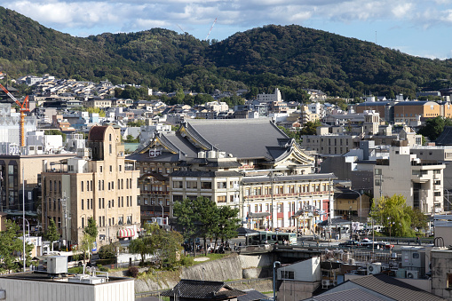 Kyoto, Japan - October 9, 2023: A view across the rooftops and skyline of the city of Kyoto, Japan, with green hills in the background.
