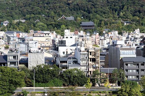 Kyoto, Japan - October 9, 2023: A view across the rooftops and skyline of the city of Kyoto, Japan, with green hills in the background.