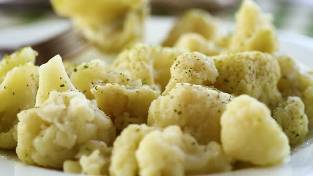 Cooked cauliflower, steamed, in a plate with spices .