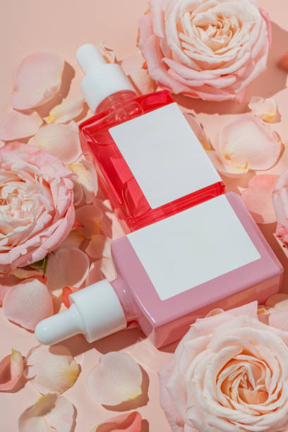 istock Composition with rose essential oil and flowers on pink background, cosmetic package mockup 1945048037