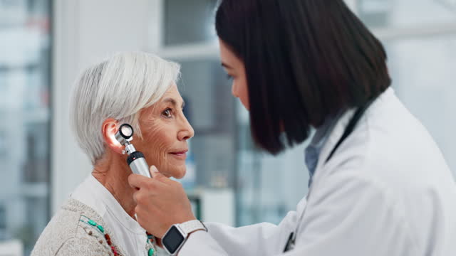 Senior woman, doctor and otoscope for ear, hearing test and exam, audio check or consultation for healthcare. Ent, otolaryngology and medical professional with elderly person for wellness in hospital