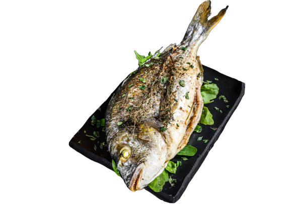 istock Roasted sea bream  fish with herbs on a cutting board.  Isolated on white background, Top view. 1945058598