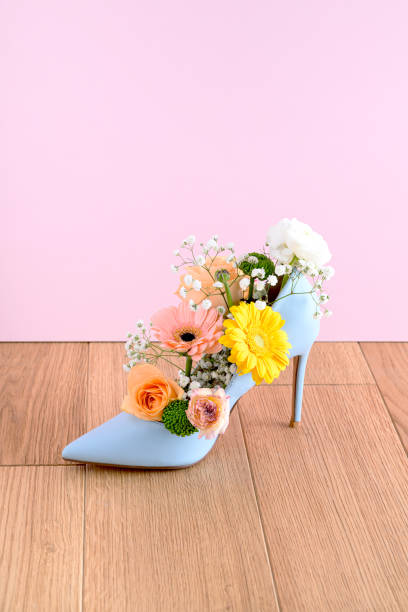 Shoes and colorful spring flowers on a blue and wood background. Summer fashion concept.