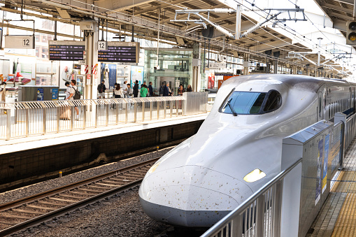 Osaka, Japan - October 11, 2023:  The Shinkansen high speed  bullet train  station platform at the Kyoto railway train station in Kyoto, Japan with e train in view.