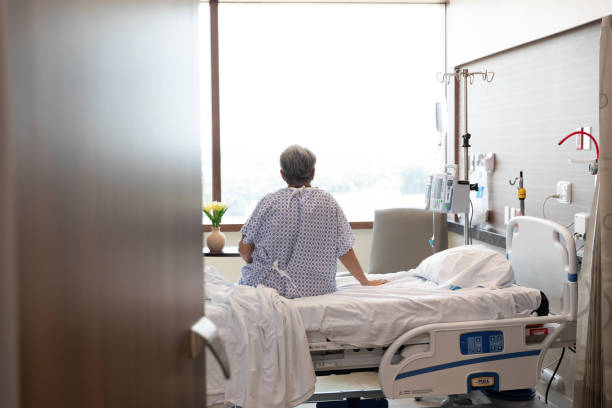 Unrecognizable female patient sits on her hospital bed The unrecognizable female patient sits alone on her hospital bed while she waits for her nurse. sick woman hospital bed stock pictures, royalty-free photos & images