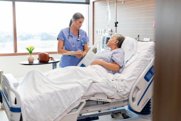 istock Female nurse stands bedside with her patient 1945087355