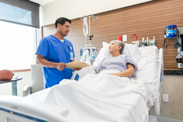 Male physician talks to his patient about her medical test results The senior adult woman lays in her hospital bed and talks with her male physician about the medical test results. Hospital stock pictures, royalty-free photos & images