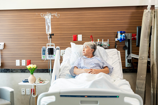 Lying in her hospital bed, the senior adult woman thinks about the results of her medical tests.
