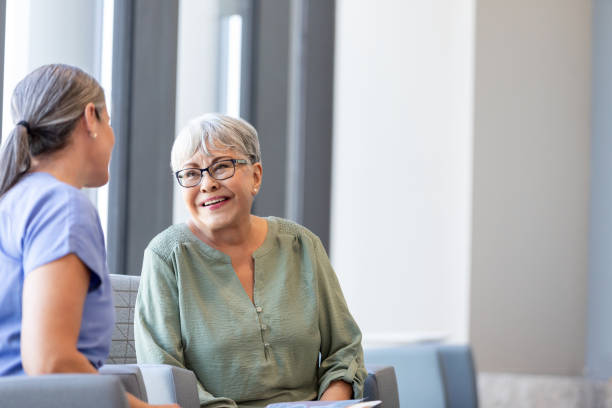 Senior adult woman smiles while talking to her doctor stock photo