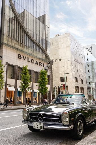 Tokyo, Japan - October 13, 2023: A photograph of a classic and vintage 1963 Mercedes-Benz SL collectors car in the busy streets of the famous Chuo-dori high end fashion shopping street of Ginza, in Tokyo, Japan